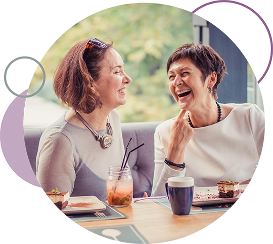 Two woman laughing over coffee after a credit card purchase.